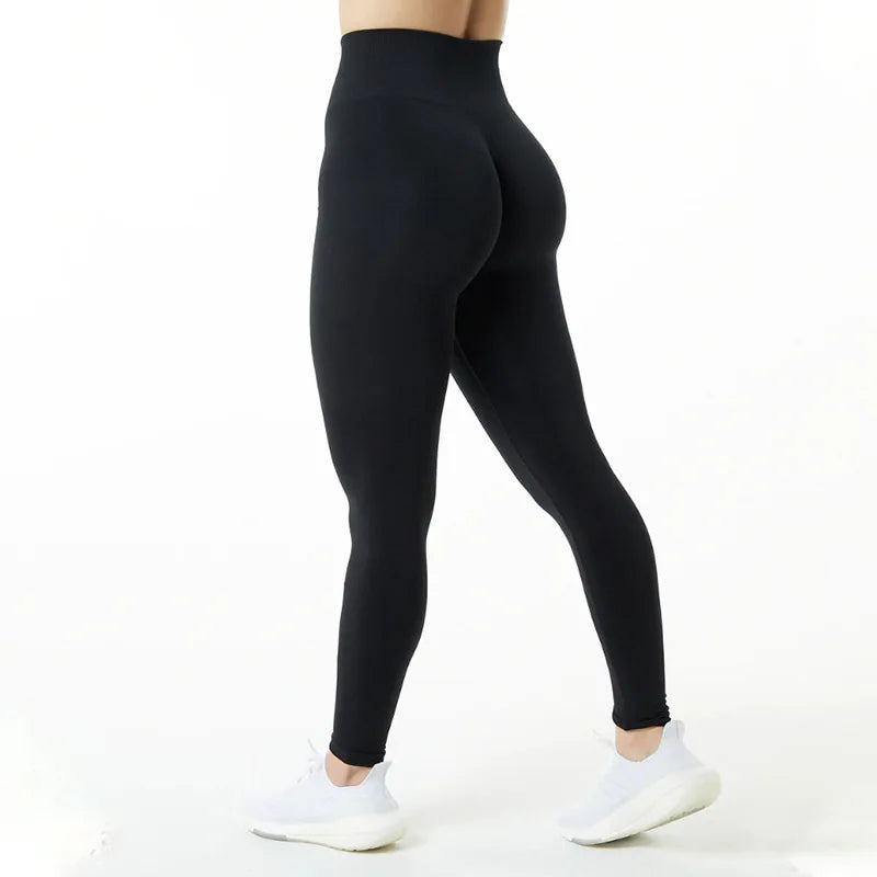Une personne portant des leggings de yoga noirs et sans couture à taille haute, debout et regardant vers le bas.