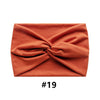 A folded terracotta orange fabric headband with a knotted design.
