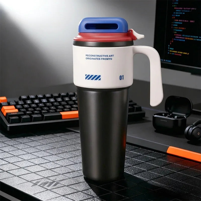 A black insulated tumbler with a white lid, red accent, and handle sits on a dark desk next to a keyboard.