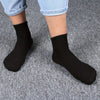 A pair of black mid-calf cotton socks worn by a person, displayed against a gray background.