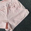 Light pink women's high-waist yoga and fitness shorts laid flat on a dark gray surface.