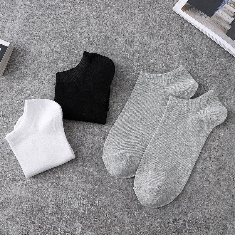 A collection of black and gray breathable men's sports ankle socks laid out on a gray surface.