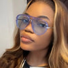 A close-up photo of a woman wearing purple-tinted aviator sunglasses with a double bridge.