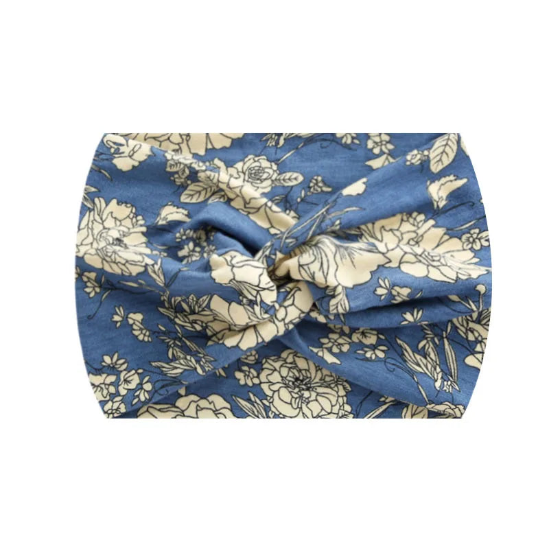 A blue fabric headband with a floral print featuring beige and white roses and leaves.