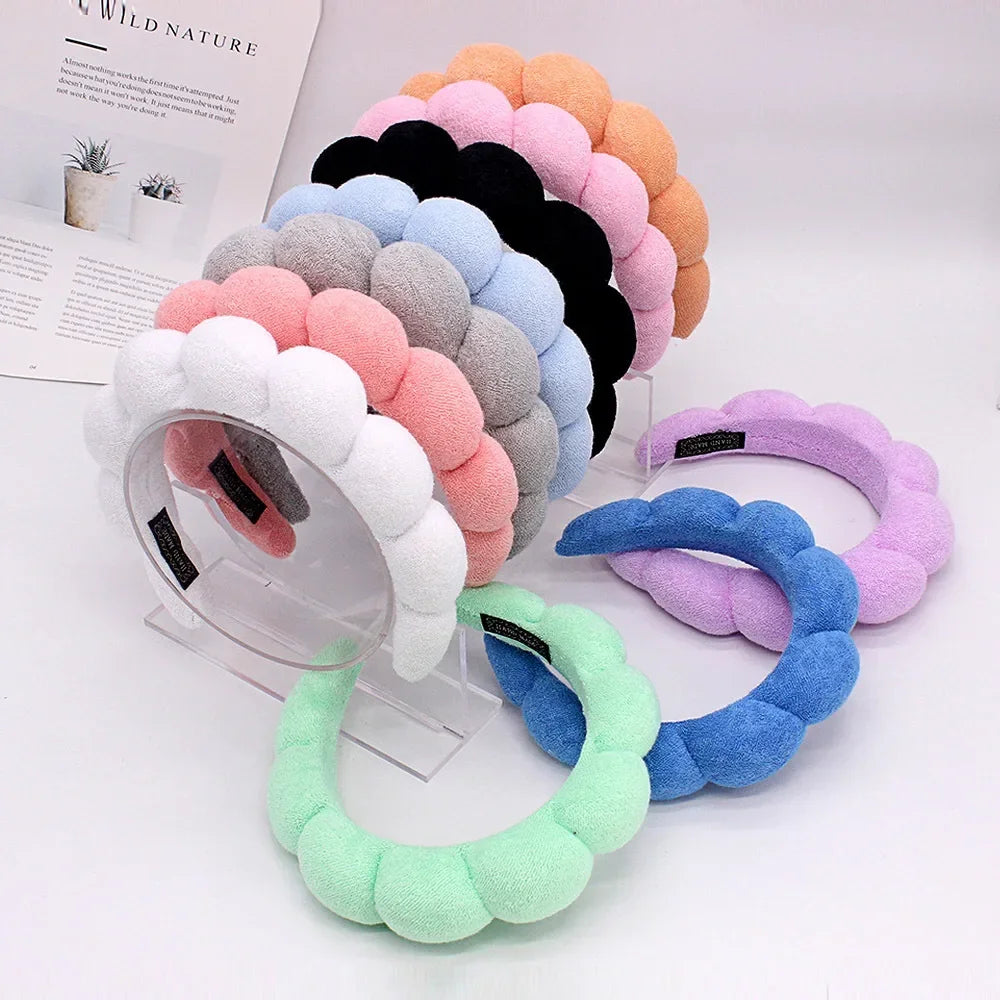 A display of colorful sponge terry cloth headbands for hair styling in various shades of pink, purple, blue, and gray.