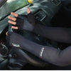 A person wearing black multi-functional sport arm sleeves is shown gripping a car steering wheel.