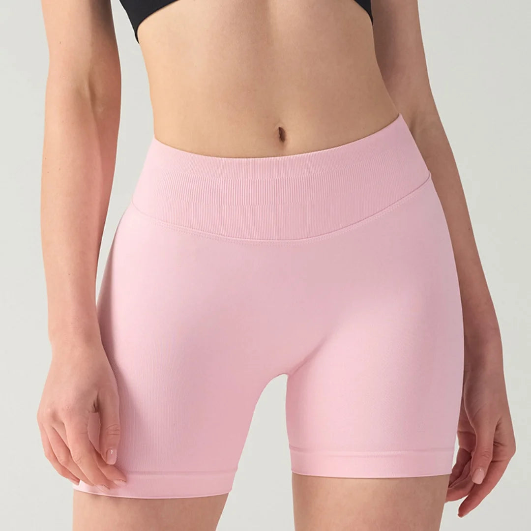 A woman is wearing light pink high-waisted knit fitness shorts.
