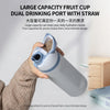 A hand holds a large capacity dual drinking port fruit cup water bottle with a straw.