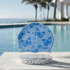 Light blue silicone swimming cap with a butterfly print resting on a white stone surface by the ocean.