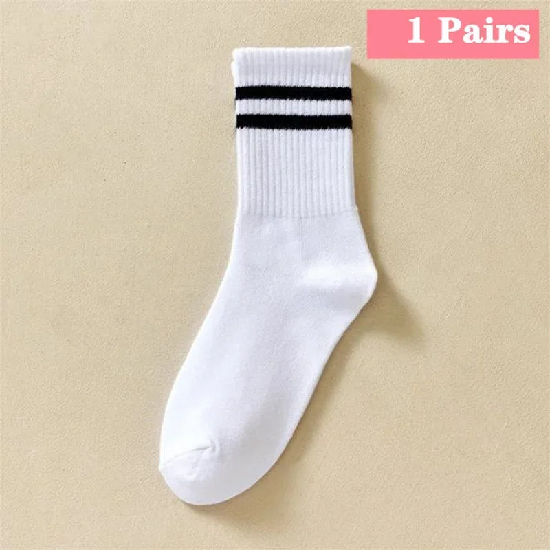 A white sock with three black horizontal stripes near the cuff, displayed on a neutral background.