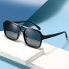 Schwarze Vintage-Sonnenbrille mit quadratischem Design auf weißem Untergrund vor blauem Hintergrund.