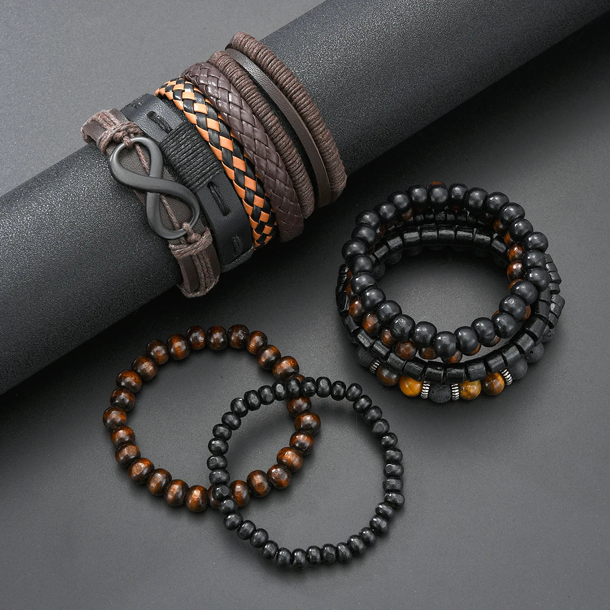 A collection of vintage beaded leather bracelets and a dark gray wrist strap are displayed on a dark surface.