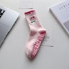 Chaussettes de yoga roses avec des cœurs brodés et une texture adhérente sur une surface blanche.