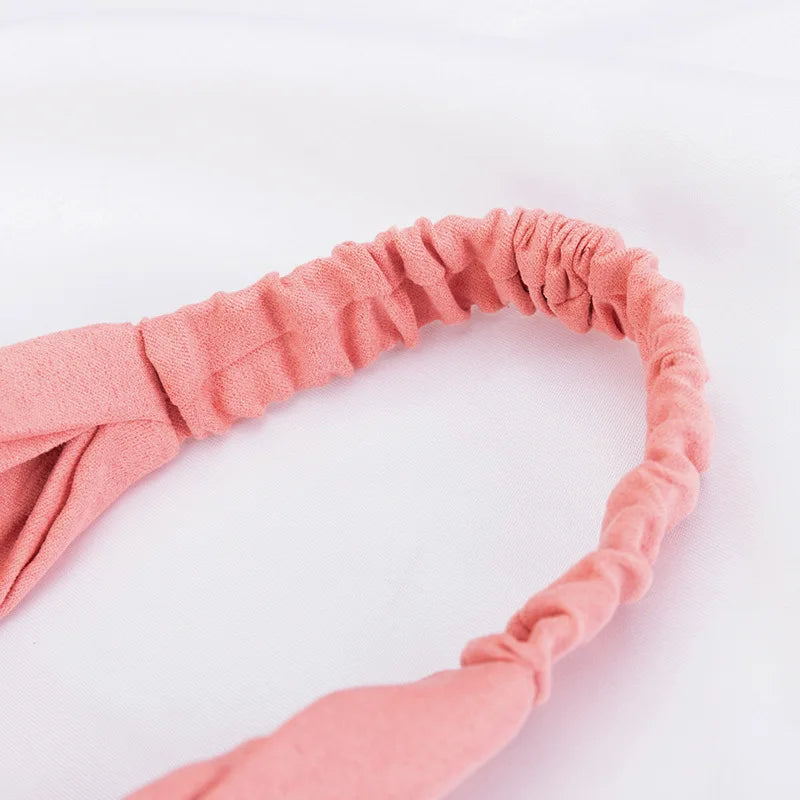 A close-up of a dusty rose chiffon headband hair accessory with gathered fabric texture.