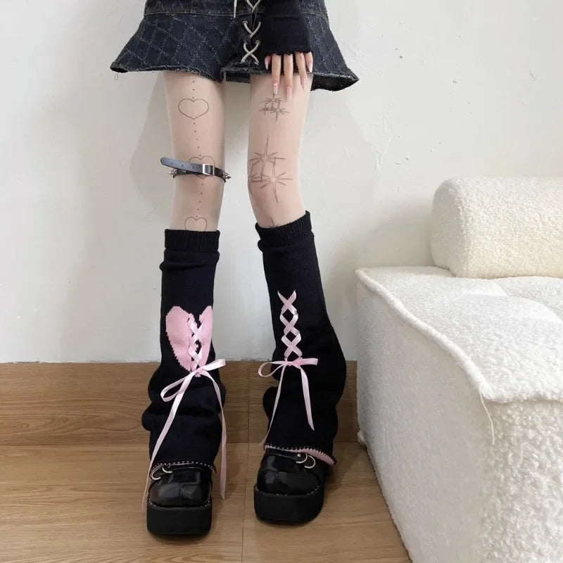 Black leg warmers with pink heart bows and lace accents worn by a person.