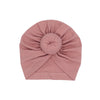 Ein fester, staubrosafarbener Baumwoll-Babyturban in Rosette-Form gefaltet.