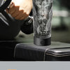 A clear, insulated sports water bottle with a black lid and measurement markings is shown next to a hand.