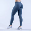 Eine Person in dunkelblauen, hochtaillierten, nahtlosen Yoga-Leggings steht und posiert.
