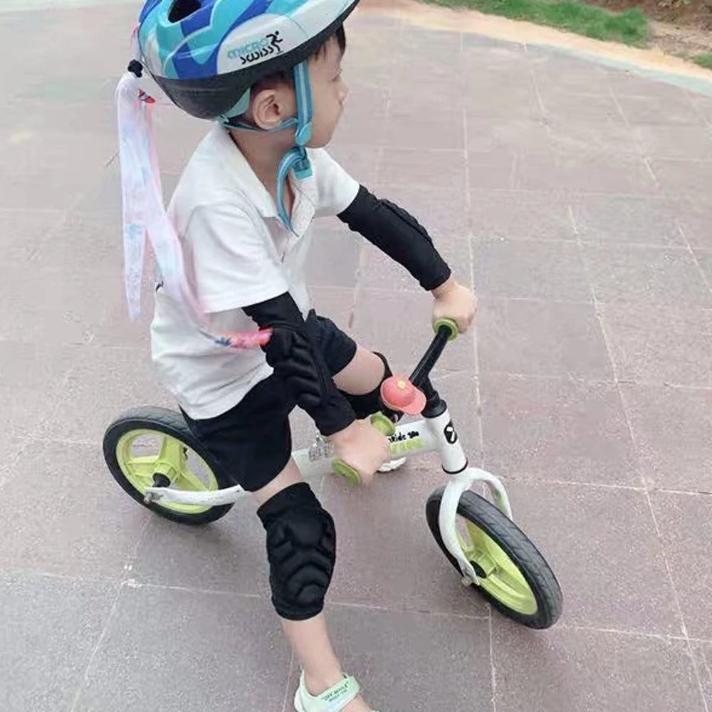 Un jeune enfant portant une chemise blanche et des protège-genoux/coudes, faisant du vélo avec des protections.