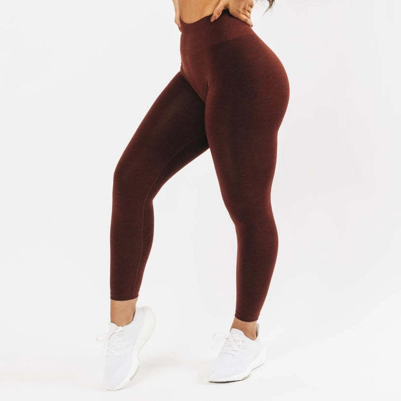 Un mannequin portant des leggings de yoga sans coutures marron foncé à taille haute et des chaussures de sport blanches.