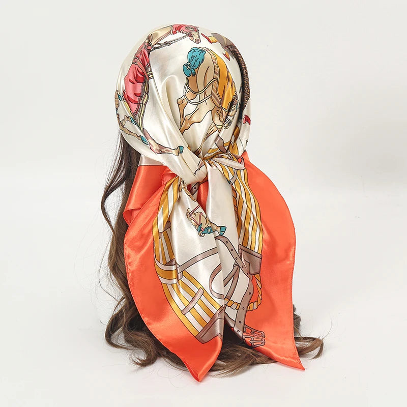 An elegant satin square scarf featuring a floral design in peach and gold tones, tied around a dark hair.