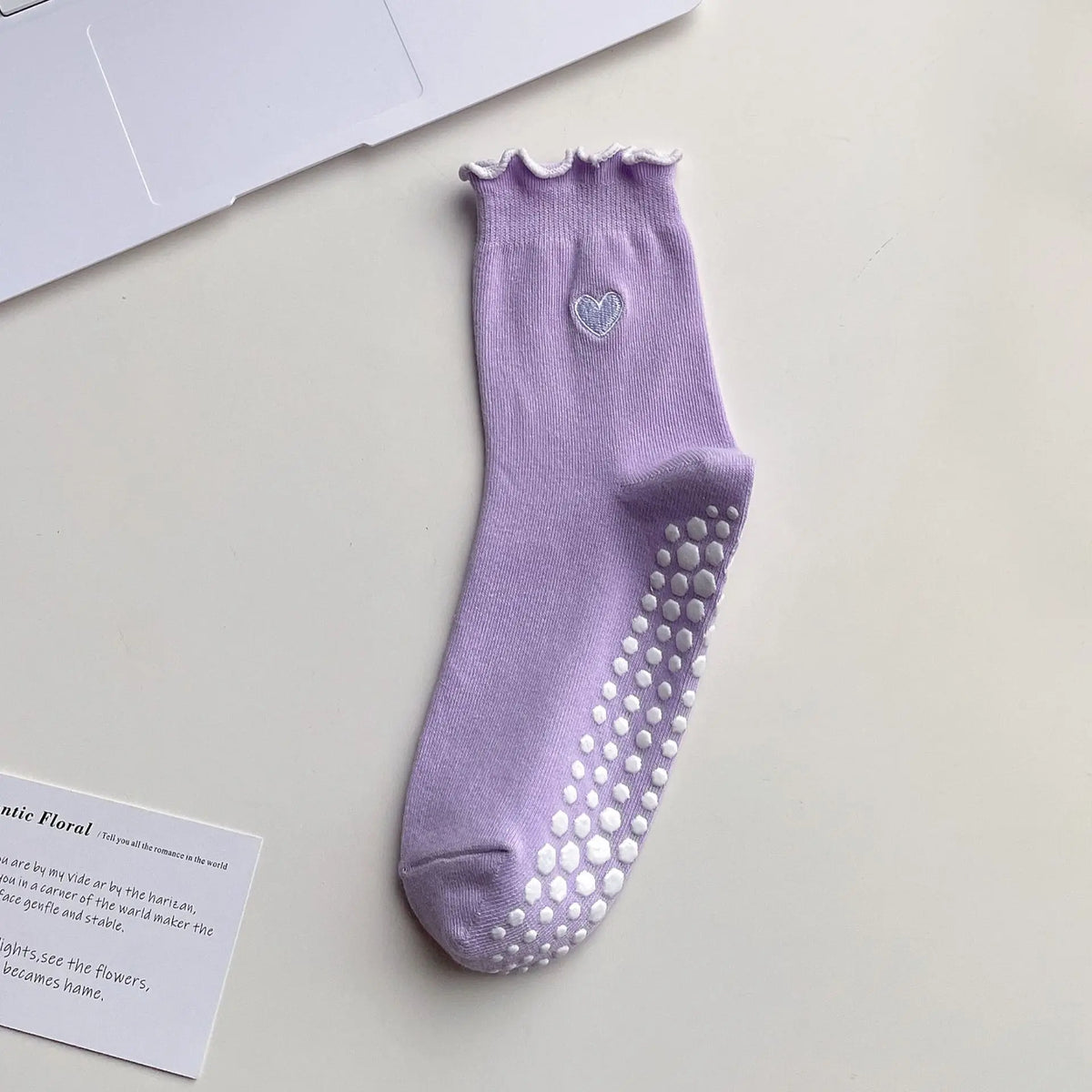 A purple yoga sock with a scalloped cuff and a heart embroidery on the toe area.