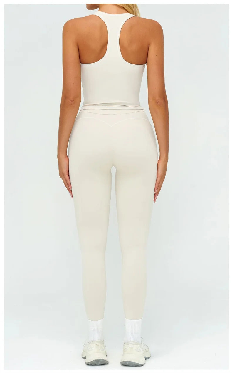Una mujer modela un conjunto de ropa deportiva de yoga crema de talle alto, que consiste en un top ajustado y leggings a jueg