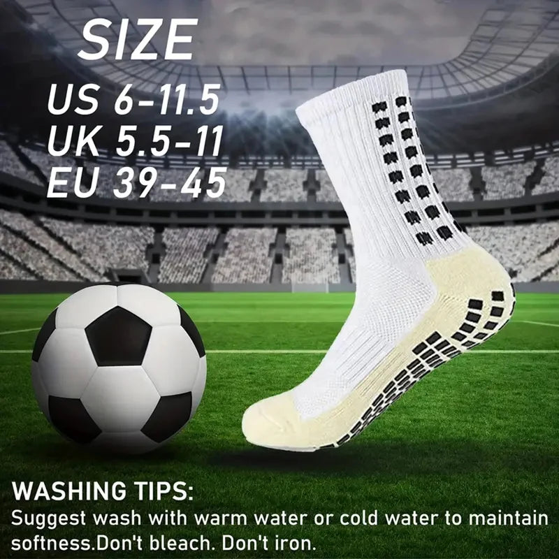 A pair of white grip soccer socks is displayed next to a soccer ball on a green field.