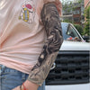 A person wearing a pink shirt displays a black sleeve design on their arm, featuring a detailed graphic.