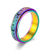 A close-up view of a stainless steel spinning ring with a colorful iridescent finish featuring moon and star designs.