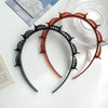 Un set de clips y diadema para el pelo con flequillo doble en negro y naranja, con intrincados diseños florales.