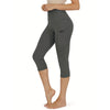 Una mujer vistiendo leggings capri deportivos de yoga grises oscuros con bolsillos de costura.