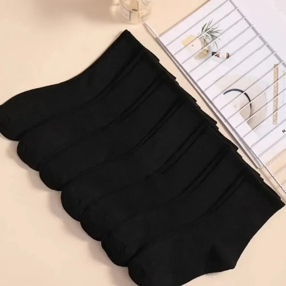Une pile de chaussettes en tricot noir mi-mollet féminines respirantes, présentées à côté d'une grille blanche.