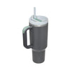 Grande tasse isotherme en acier inoxydable avec une paille verte et un corps gris.