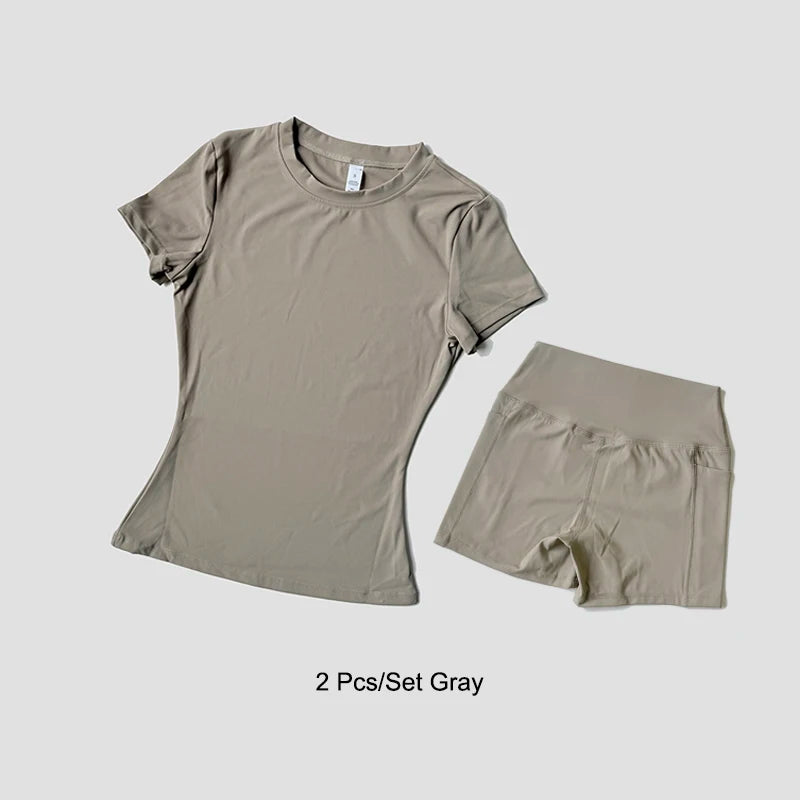 Un conjunto de dos prendas de yoga grises de talle alto para mujeres, incluyendo una camiseta y shorts.