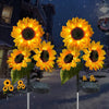 Three bright yellow solar sunflower LED stake lights are displayed against a snowy night background.