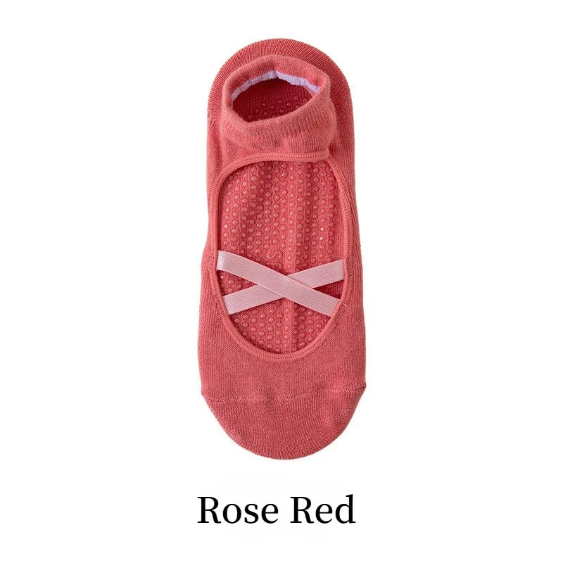 A pair of rose red yoga socks with a crisscross strap design.