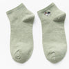 A pair of light green knitted cotton socks with a small black and white dog embroidery on the foot.