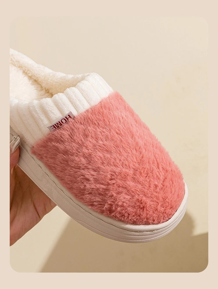 A close-up of cozy plush fleece slippers in pink and cream colors shown from the side.