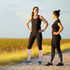 Two women wearing compression socks for circulation and recovery standing outdoors on a gravel path.