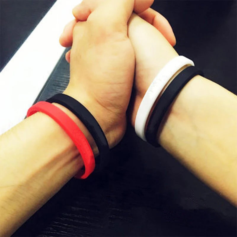 Two hands clasped together showing black, red, and white silicone wristbands on wrists.