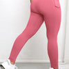 A woman wearing pink high-waisted sports leggings and white sneakers.