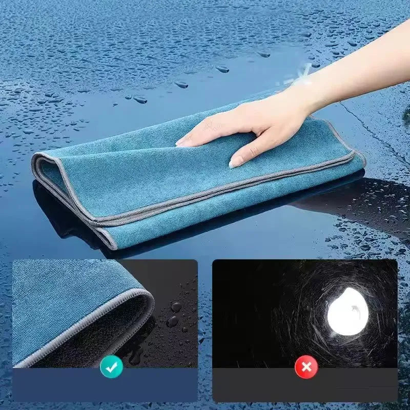 A hand is holding a blue microfiber car cleaning towel on a wet surface, showing the texture and absorbency.