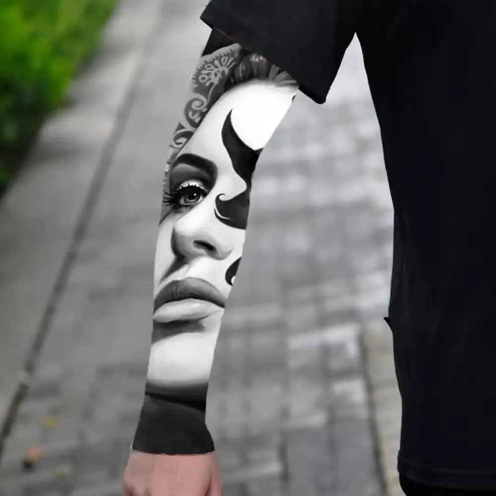 Close-up of a person wearing black arm sleeves with intricate black and white tribal designs.