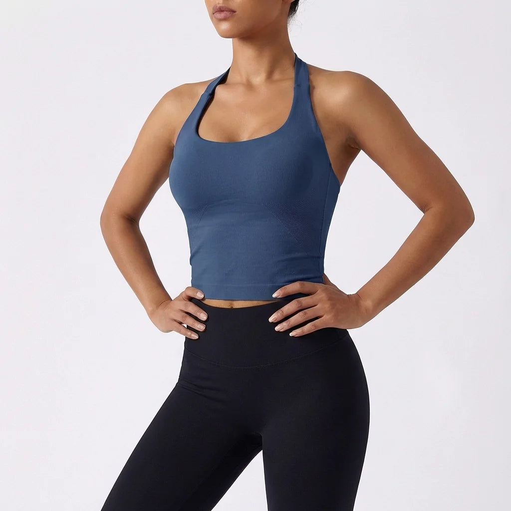 A model wearing a dark blue seamless yoga and pilates sports bra and black leggings.