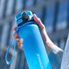 Eine Hand hält eine leuchtend blaue Sportflasche mit Trageleine vor einem verschwommenen Hintergrund.