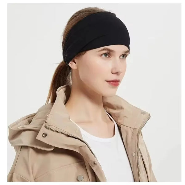 Une femme portant un bandeau de sport noir et une veste beige, regardant sur le côté.