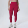 A model wearing high-waisted, deep red leggings and white socks, standing against a light background.