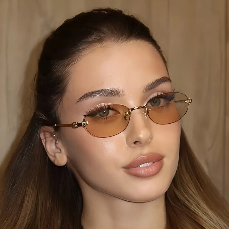 Close-up of a woman wearing rimless oval gradient sunglasses with gold accents.
