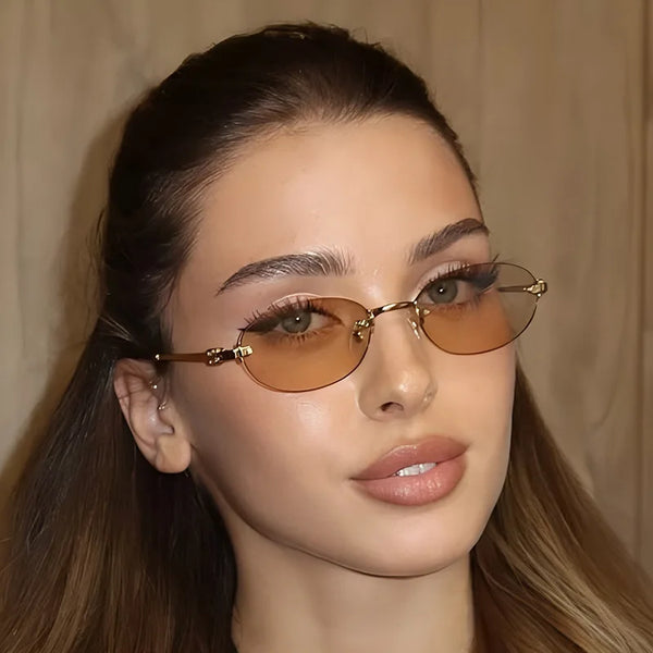 Close-up of a woman wearing rimless oval gradient sunglasses with gold accents.